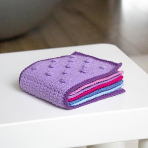 Handmade crochet sensory book made from a detailed PDF pattern, an ideal educational and interactive toy for babies and kids.