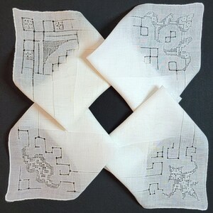 May include: Four white handkerchiefs arranged in a pinwheel pattern. Each handkerchief features a detailed embroidered design in the corners, with geometric and floral patterns. The fabric appears to be a fine linen or cotton.