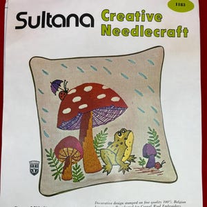May include: Sultana Creative Needlecraft Crewel Kit No. 1183 Sun Shower 14 inch square knife edge pillow. The package features an embroidery design of a large red mushroom, a smaller purple mushroom, a green frog, and a ladybug with an umbrella.