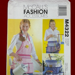 May include: McCall's Fashion Accessories pattern envelope. The cover features images of aprons and gardening tool organizers. The main image shows a woman wearing a pink and white striped apron with pockets, holding a watering can.