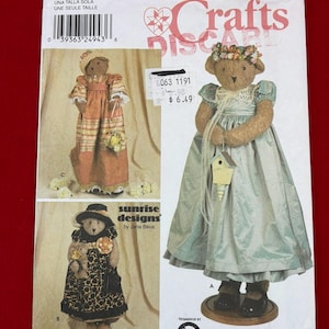 May include: A Simplicity 9695 sewing pattern envelope for stuffed bears. The cover displays three bears dressed in different outfits: a peach plaid dress, a black leopard print dress, and a light blue dress with a small wooden birdhouse accessory.