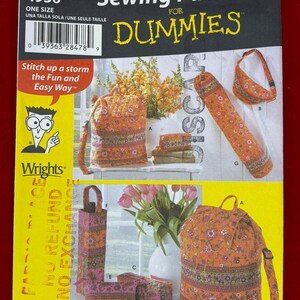 May include: A Simplicity 4936 sewing pattern envelope for quilted bags, featuring the text Sewing Patterns for Dummies. The cover displays various orange and pink floral quilted bag designs, including backpacks, pouches, and a yoga mat carrier.