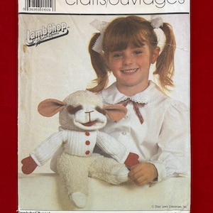 May include: A Simplicity 7989 sewing pattern envelope for a Lamb Chop puppet. The cover features a photograph of a child with pigtails next to a finished cream-colored plush lamb puppet with brown ears, a white shirt, and red buttons.