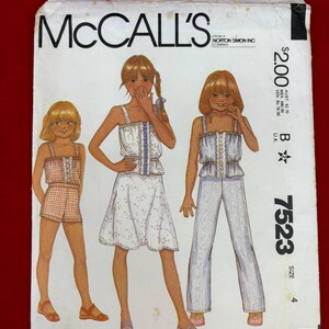 May include: A McCall's 7523 sewing pattern envelope for size 4, featuring illustrations of three outfits: a plaid romper, a floral skirt set, and a patterned pant set. The white paper envelope includes the brand name, pattern number, and price.