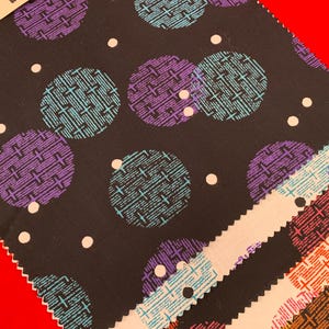 May include: Close-up of a black fabric with a repeating pattern of large circles in teal and purple, each with a crosshatch design. Small white dots are scattered across the background. Several fabric swatches are visible.