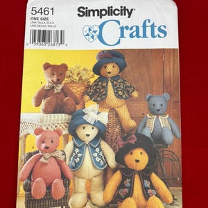 May include: A Simplicity 5461 sewing pattern envelope for stuffed bears. The cover displays six teddy bears in various colors, including brown, pink, blue, and yellow, wearing hats and vests. The text reads Simplicity 5461 Crafts and Elaine Heigl Designs.