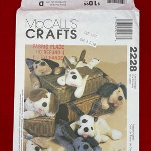 May include: A McCall's Crafts 2228 sewing pattern envelope featuring an illustration of five plush toy dogs in various colors and patterns, including brown, white, black, and plaid, resting on woven baskets with text including the pattern number 2228.