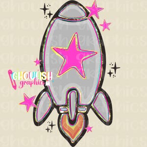 May include: A whimsical illustration of a rocket ship in shades of gray, black, and gold, with a large pink star in the center. Additional pink stars and black starbursts surround the rocket. The text "Ghoulish Graphics" is also present.