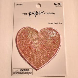 May include: A pink heart-shaped sticker patch with iridescent glitter. The sticker patch is packaged on a white card with the text "THE paper STUDIO" and "Sticker Patch, 1 pc".