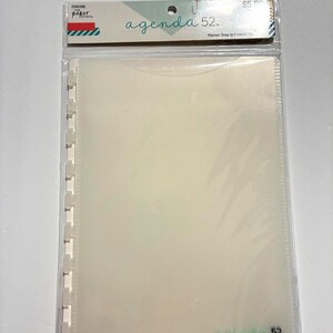May include: A clear plastic planner snap-in pocket with the text "agenda 52" and "Planner Snap in Pockets". The packaging includes a label with the text "paper studio". The pocket is designed to hold planner inserts.