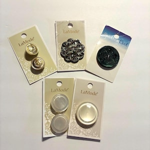 May include: Assortment of buttons on cards. Includes gold, silver, and iridescent buttons. Some cards have the "LaMode" logo, and one has "Spectrum Cool". Buttons vary in shape and design, suitable for sewing and crafts.
