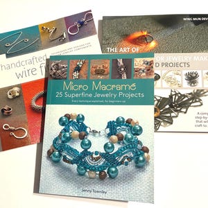 May include: A collection of jewelry-making books, including "Handcrafted Wire Forms," "Micro Macramé," and "The Art of Jewelry Makers." The books feature various jewelry projects and techniques, with colorful cover designs and detailed illustrations.