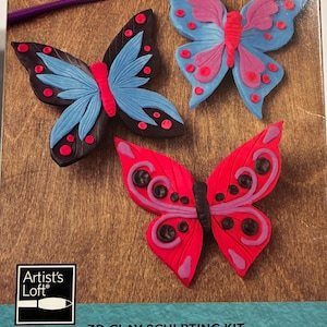 May include: A 3D clay sculpting kit featuring three colorful butterfly designs. The butterflies are red, blue, and pink with black accents. The kit includes a purple sculpting tool and a ball of pink clay. The package reads "3D Clay Sculpting Kit".