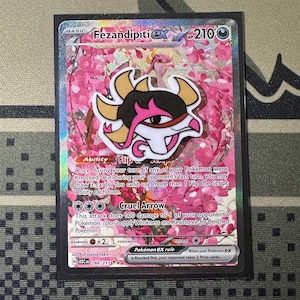 May include: A Fezandipiti ex trading card featuring a pink cherry blossom background and a central stylized creature illustration. The card displays 210 HP, the Flip the Script ability, and the Cruel Arrow attack, with the number 288/217 at the bottom.