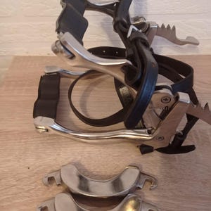 Könnte beinhalten: Eine Sammlung von Reitausrüstung, darunter ein Pferdemaul mit einem schwarzen Lederzaum und Zügeln sowie zwei zusätzliche silberfarbene Backenstücke. Die Metallkomponenten haben eine polierte Oberfläche.