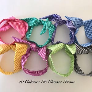 May include: Eight fabric headbands featuring a small gingham check pattern in various colours including pink, teal, purple, blue, yellow, magenta, light green, and black. Each headband has a knotted top detail. Text reads: 10 Colours To Choose From.