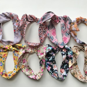May include: Assortment of ten colourful headbands with various floral and geometric patterns. The headbands are made of fabric and have a knotted design.
