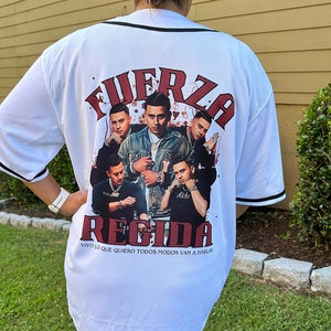 Puede incluir: Jersey de b&eacute;isbol blanco con un estampado gr&aacute;fico rojo y negro de un grupo de hombres con el texto "FUERZA REGIDA" y "VIVO LO QUE QUIERO TODOS MODOS VAN A HABLAR" en la espalda.