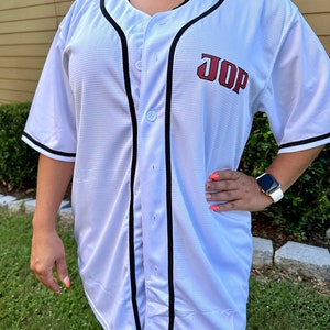 Puede incluir: Jersey de b&eacute;isbol blanco con ribetes negros y letras rojas que dicen "JOP".