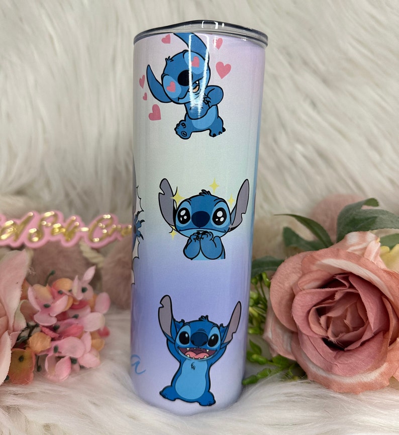 May include: A blue and white stainless steel tumbler with a gradient design featuring multiple images of Stitch from Lilo & Stitch. The tumbler has a clear lid.