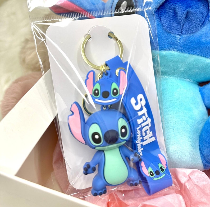 Puede incluir: Llavero Stitch azul con un personaje Stitch azul y verde y una correa azul con el texto "Stitch Lovely Baby".