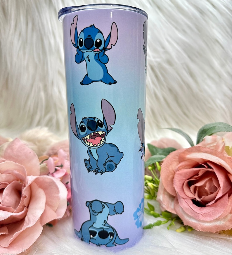 Puede incluir: Un vaso de acero inoxidable azul y morado con un patr&oacute;n repetido de Stitch de Lilo & Stitch. El vaso tiene una tapa transparente.