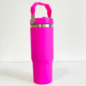 May include: A vibrant, hot pink insulated tumbler with a matching handle and lid. The stainless steel rim and handle hardware provide a contrasting metallic accent. This reusable water bottle is designed to keep drinks cold or hot.