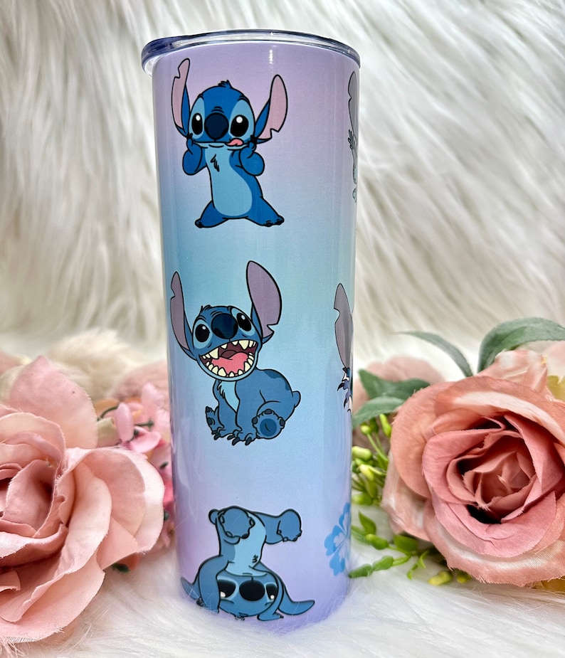 May include: A blue and purple stainless steel tumbler with a repeating pattern of Stitch, a blue alien character from the Disney movie Lilo & Stitch.
