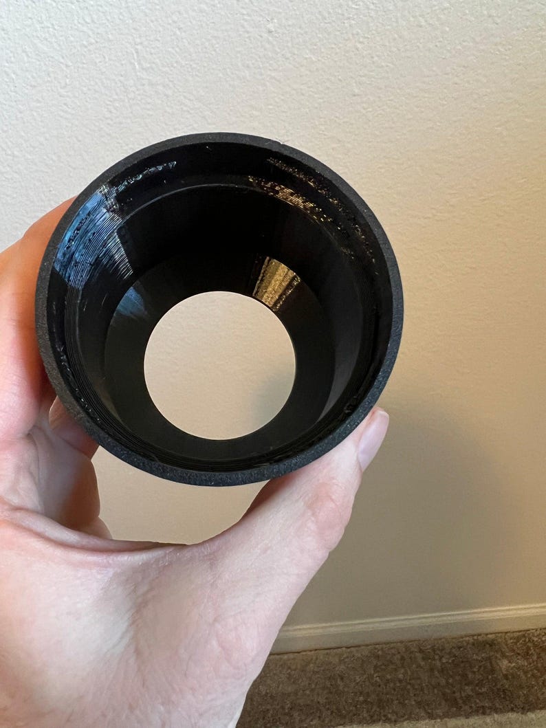 Puede incluir: Un embudo de pl&aacute;stico negro con un interior liso y redondeado. El embudo est&aacute; dise&ntilde;ado para guiar l&iacute;quidos hacia una abertura m&aacute;s peque&ntilde;a.