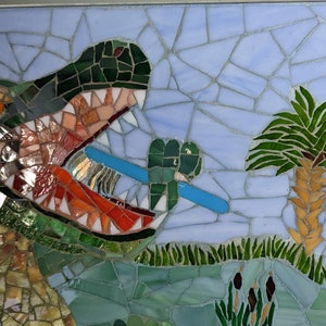May include: A mosaic artwork depicting a green alligator with its mouth open, holding a blue toothbrush. The alligator is in a swamp setting with green grass and a palm tree.