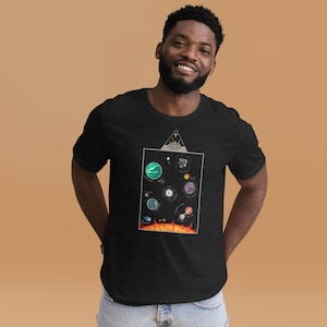 Puede incluir: Una camiseta negra con un gráfico de un sistema solar con el texto "Outer Worlds" y "Planets" impreso en ella.