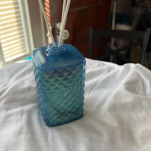 May include: A blue glass diffuser bottle with a diamond pattern and white diffuser sticks.