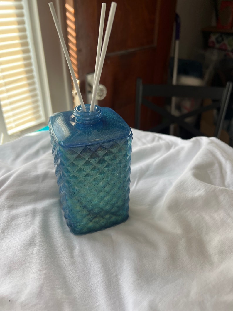 May include: A blue glass diffuser bottle with a diamond pattern and white diffuser sticks.