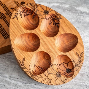Peut inclure: Un porte-&oelig;ufs en bois avec cinq compartiments individuels pour contenir des &oelig;ufs. Le porte-&oelig;ufs est d&eacute;cor&eacute; d'un motif floral et a une finition en bois naturel.