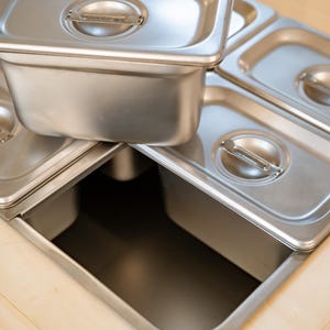 Close-up of stainless steel food containers in cart cutouts