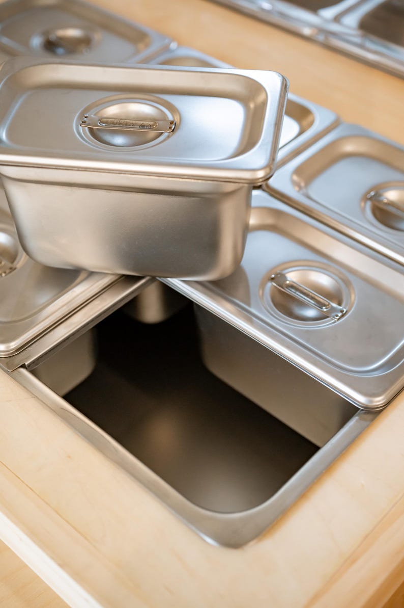 Close-up of stainless steel food containers in cart cutouts