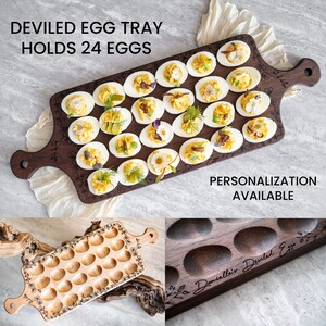 K&ouml;nnte beinhalten: Ein Holztablett mit dunkelbrauner Oberfl&auml;che, das f&uuml;r 24 gef&uuml;llte Eier ausgelegt ist. Das Tablett ist mit einem dekorativen Blumendesign und dem Text "DEVILED EGG TRAY HOLDS 24 EGGS" verziert. Das Tablett ist mit gef&uuml;llten Eiern gef&uuml;llt, die jeweils mit einer anderen Garnitur wie Petersilie, Schnittlauch und Paprika verziert sind.