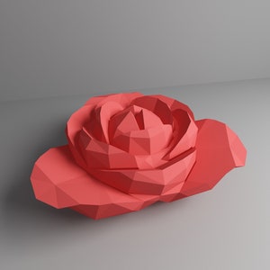 May include: A coral-colored, geometric paper rose with detailed petal construction. The low-poly design gives the flower a modern, artistic look. The rose is set against a neutral gray background, highlighting its vibrant color and unique form.