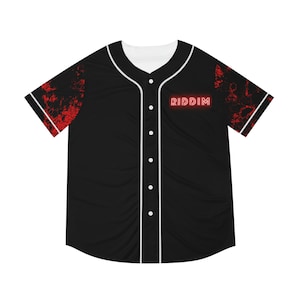 May include: Black baseball jersey with white trim and buttons. The jersey features red splatter designs on the sleeves and the word "RIDDIM" in red neon lettering on the chest. The jersey has a white collar.