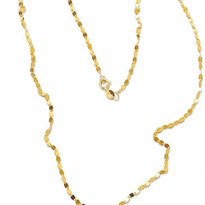 Könnte beinhalten: Eine zarte Goldkette mit einer Reihe kleiner, flacher, oval geformter Glieder. Die Halskette hat einen einfachen Verschluss und wird vor einem weißen Hintergrund gezeigt. Die Kette hat eine helle, glänzende Goldfarbe.