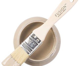 May include: A round container of light beige mineral paint with a wooden paintbrush resting across the top. The brush handle is printed with the text FUSION MINERAL PAINT and the metal ferrule shows a width of 1 inch.