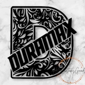 May include: A black and silver decorative sign featuring a large letter D with an intricate filigree pattern cut out of the center. The word DURAMAX is displayed in bold black capital letters diagonally across the face of the letter D.