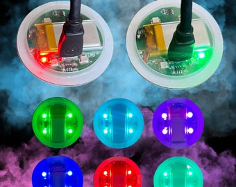 May include: Six round, flat, LED light panels with different colored lights. The lights are arranged in a circle with a black wire coming out of the top of each panel. The panels are on a white background with a blue and gray smoke effect.
