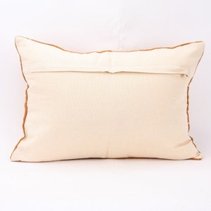 May include: A white pillow with a brown border. The pillow has a zipper closure on the back.