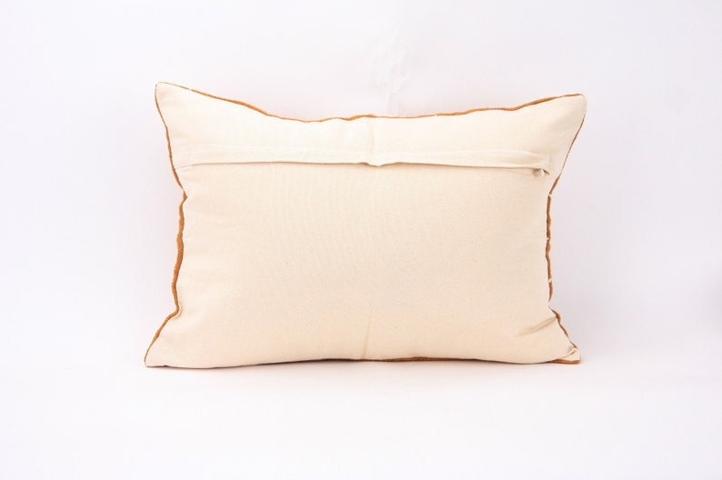 May include: A white pillow with a brown border. The pillow has a zipper closure on the back.
