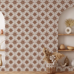 May include: A beige wall with a repeating pattern of brown starburst shapes. The wall is decorated with a vase of dried flowers and a shelf with decorative items.
