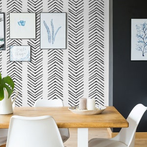 May include: A dining room with a white table and chairs, a black and white chevron patterned wallpaper, and black framed artwork on the wall.