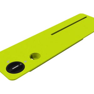 May include: A lime green rectangular object with a black dial and a circular hole. The object has a groove running along its length. The dial has a white arrow. The object is on a white background.