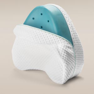 May include: A white, textured knee pillow with a teal gel insert. The pillow has a zip closure and is designed for comfort and support. The gel insert has several small holes.