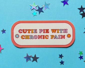 May include: A pink and white sticker with the text "Cutie Pie With Chronic Pain" in rainbow colors. The sticker is surrounded by silver glitter stars on a light blue background.